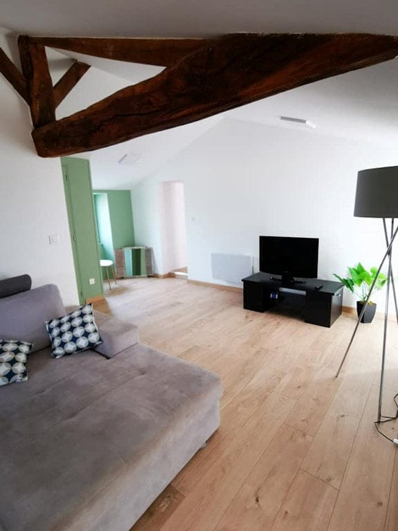 Salon lumineux du gîte Le Graizeau avec poutres apparentes, canapé confortable et télévision, situé en Vendée